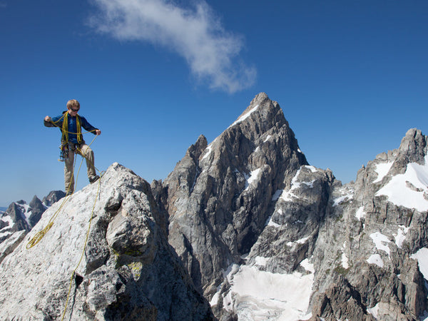 IFMGA Mountain Guide Mark Smiley standing on a summit block along the Grand Traverse with the Grand Teton behind him