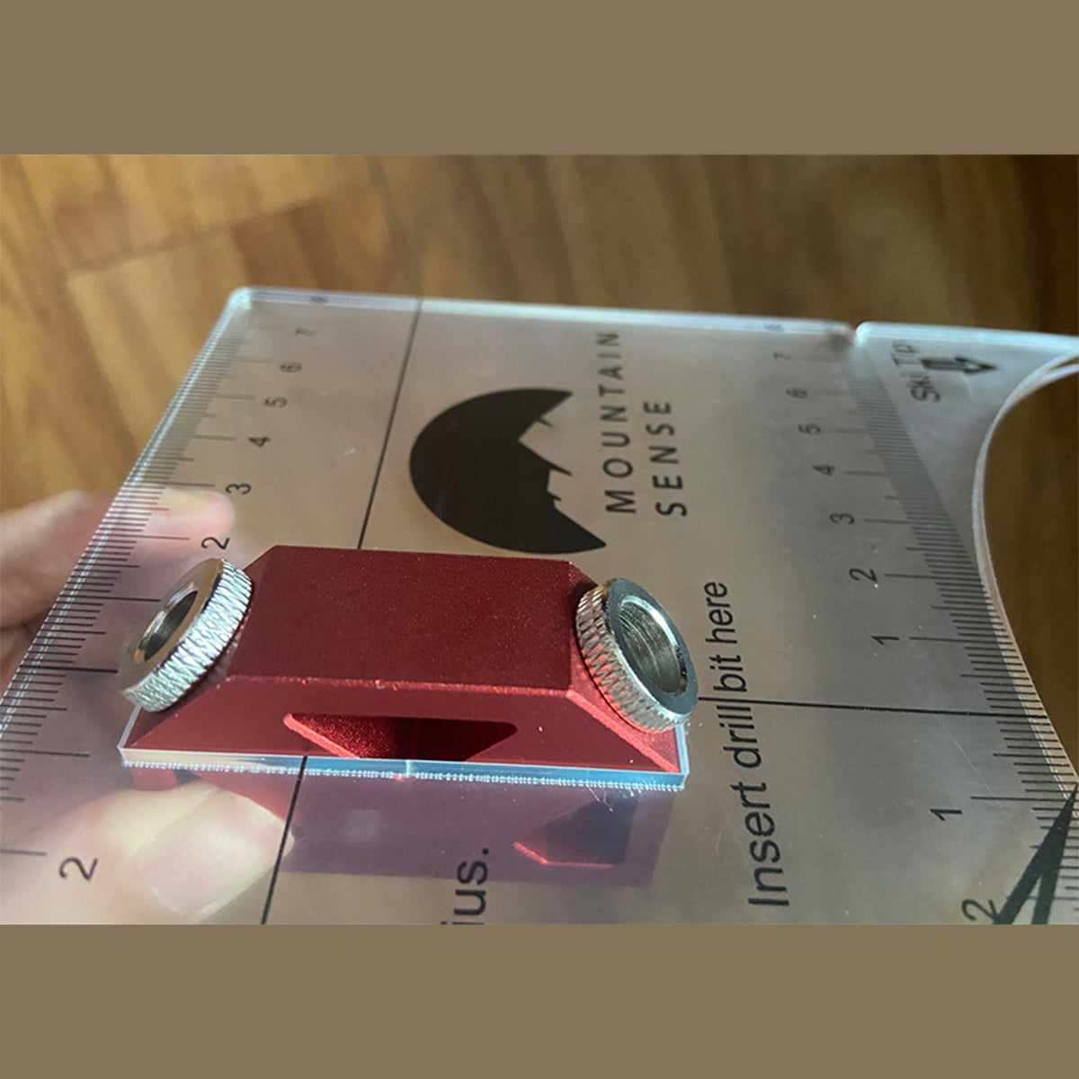 Red aluminum drilling jig held on the clear Mountain Sense hole guide, showing the drill bit insert point