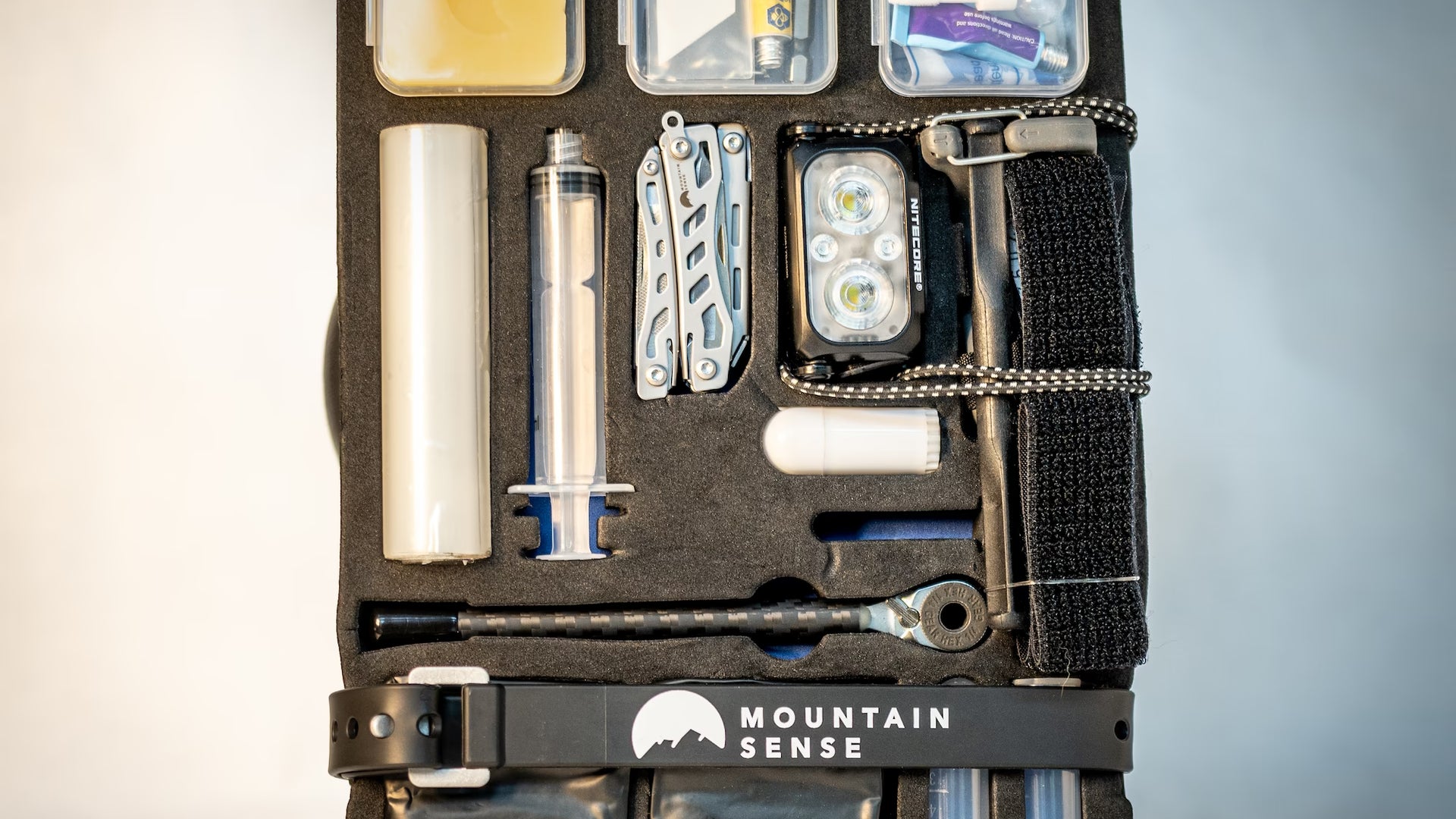 Mountain Sense Backcountry Rescue Kit laid open flat, showing repair tools, hemostatic gauze, headlamp and tourniquet in labeled compartments