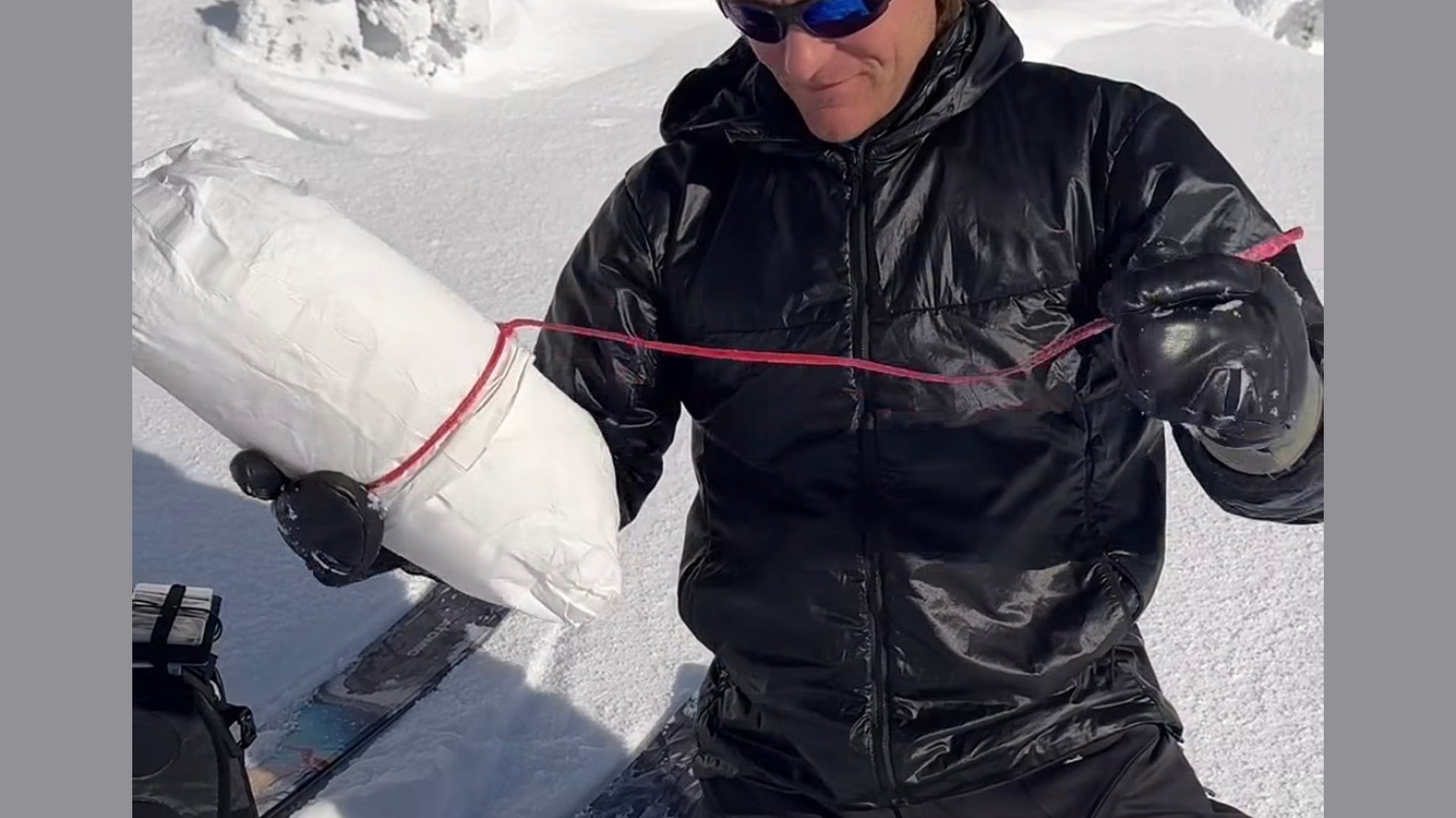 Mark Smiley pulling on the red cord of a snow filled T-Trench Stuff Sack anchor, captioned would you rap off of this