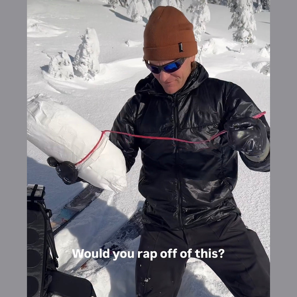 Mark Smiley pulling on the red cord of a snow filled T-Trench Stuff Sack anchor, captioned would you rap off of this